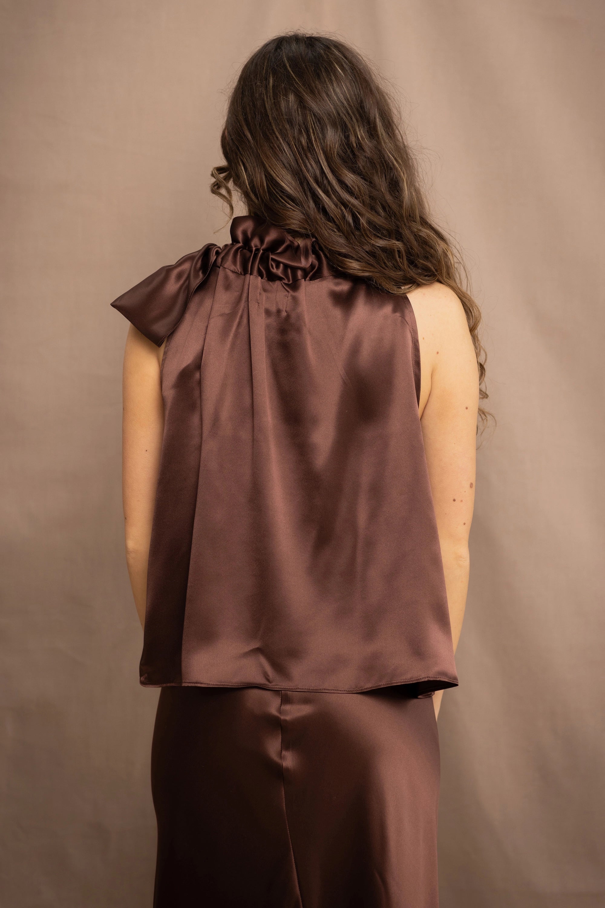 a woman wears a pure 100% silk halter top in chocolate brown with matching silk skirt