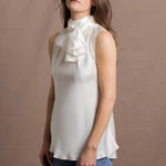 A woman wears a 100% silk pussybow sleeveless blouse in white