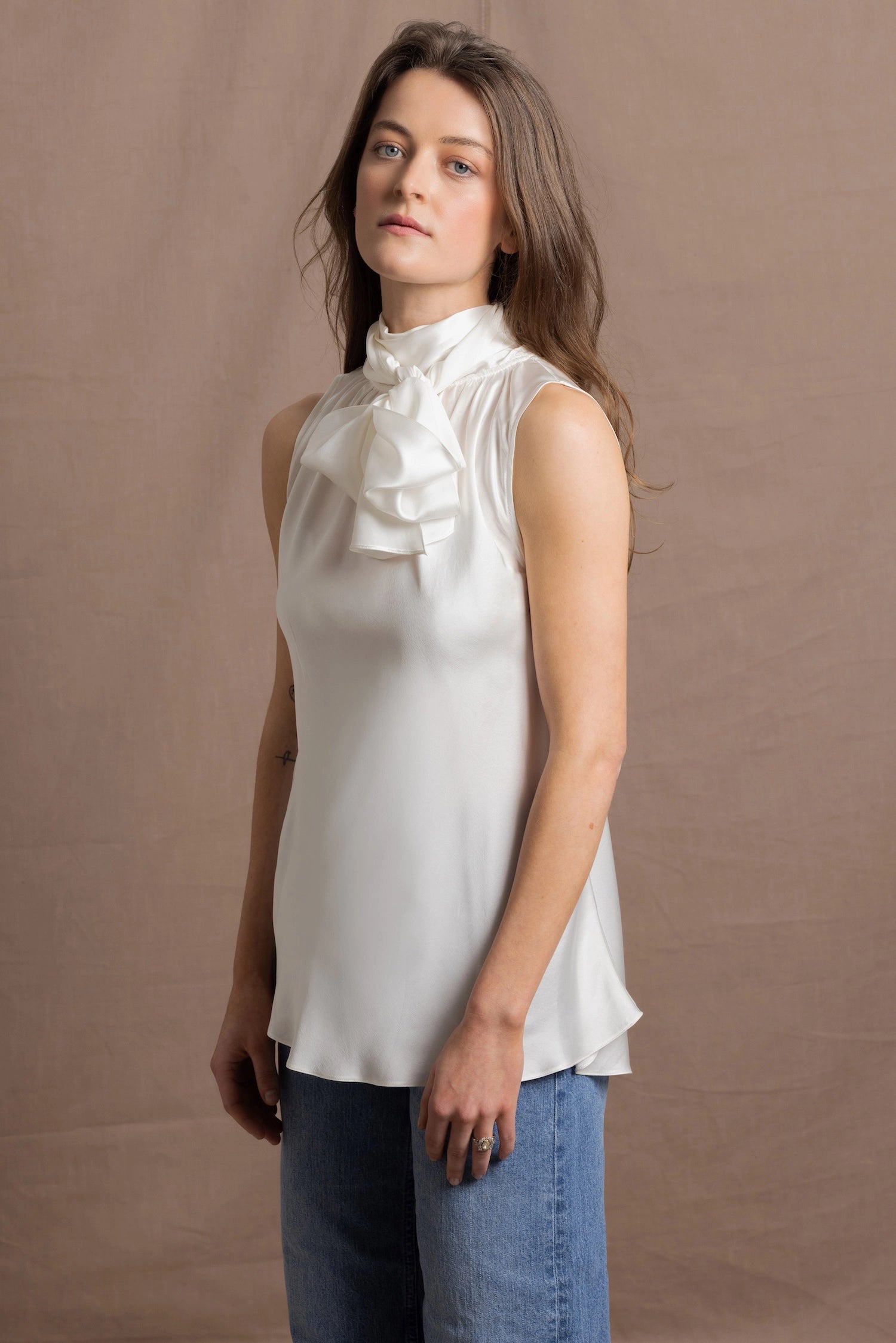A woman wears a 100% silk pussybow sleeveless blouse in white