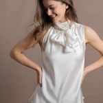 A woman wears a 100% silk pussybow sleeveless blouse in white