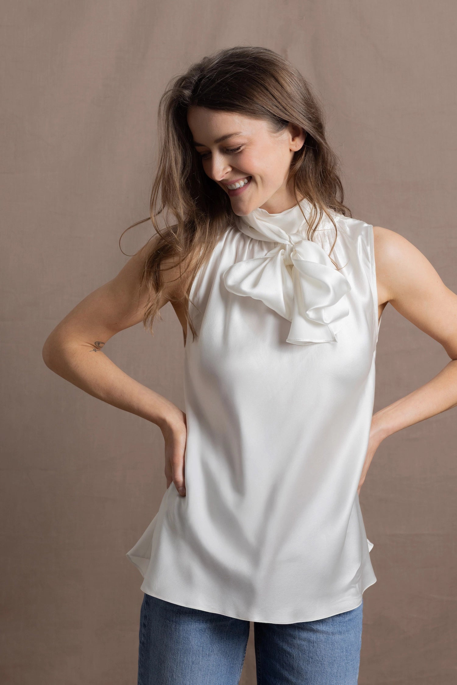 A woman wears a 100% silk pussybow sleeveless blouse in white
