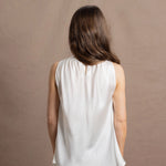 A woman wears a 100% silk pussybow sleeveless blouse in white