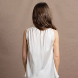 A woman wears a 100% silk pussybow sleeveless blouse in white