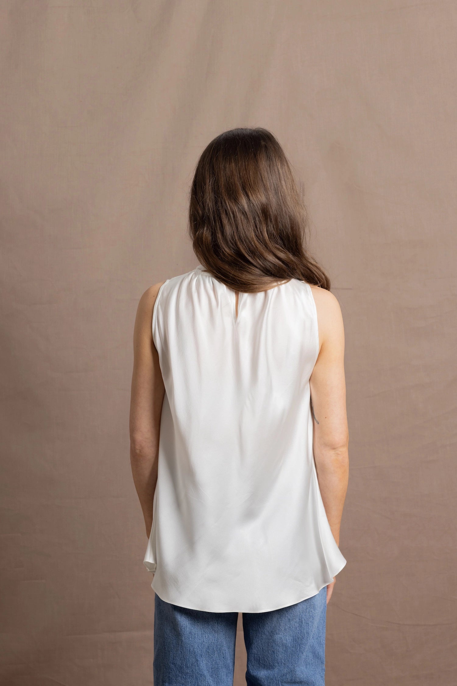 A woman wears a 100% silk pussybow sleeveless blouse in white