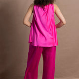 A woman wears a 100% silk pussy bow top in bright pink with matching trousers