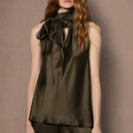 Woman wearing an olive green sleeveless silk top with a bow 