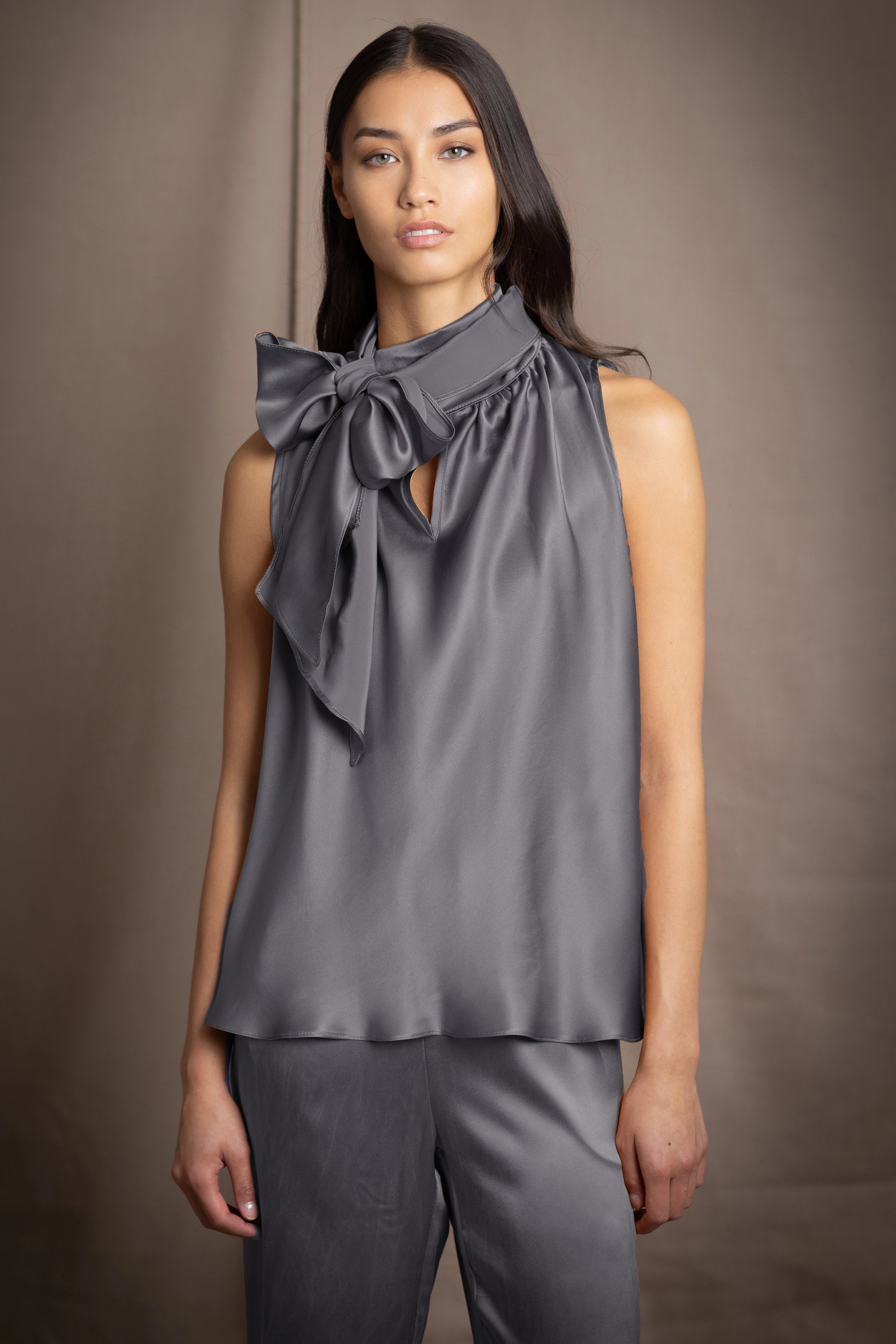 Woman wearing a dark gray pussy bow silk blouse with matching trousers