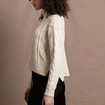 A woman wears a traditional Irish Aran Sweater made in 100% Cashmere over a black silk skirt