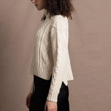 A woman wears a traditional Irish Aran Sweater made in 100% Cashmere over a black silk skirt