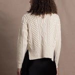 A woman wears a traditional Irish Aran Sweater made in 100% Cashmere over a black silk skirt
