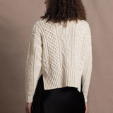 A woman wears a traditional Irish Aran Sweater made in 100% Cashmere over a black silk skirt