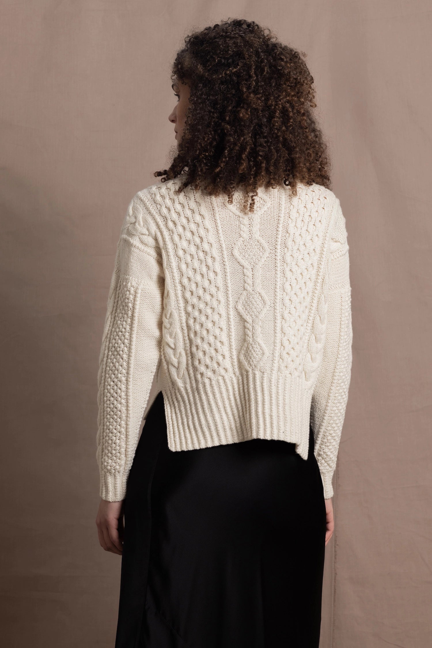 A woman wears a traditional Irish Aran Sweater made in 100% Cashmere over a black silk skirt