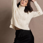 A woman wears a traditional Irish Aran Sweater made in 100% Cashmere over a black silk skirt