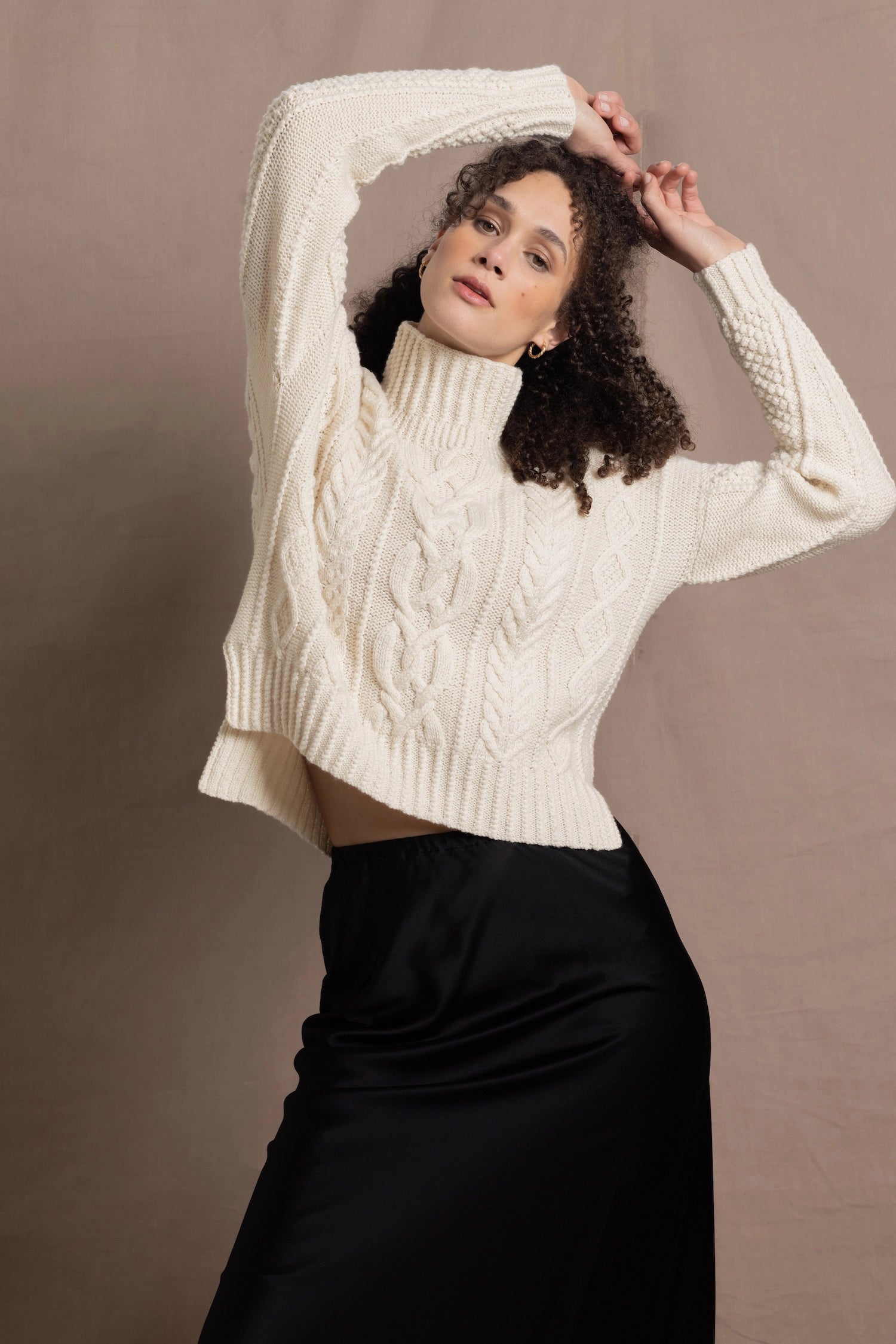 A woman wears a traditional Irish Aran Sweater made in 100% Cashmere over a black silk skirt