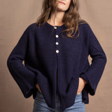 A woman wears a pure cashmere oversized cardigan with 4 buttons at the top in Navy Blue over a pair of jeans