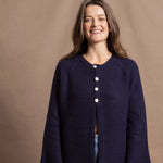 A woman wears a pure cashmere oversized cardigan with 4 buttons at the top in Navy Blue over a pair of jeans