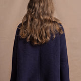 A woman wears a pure cashmere oversized cardigan with 4 buttons at the top in Navy Blue over a pair of jeans