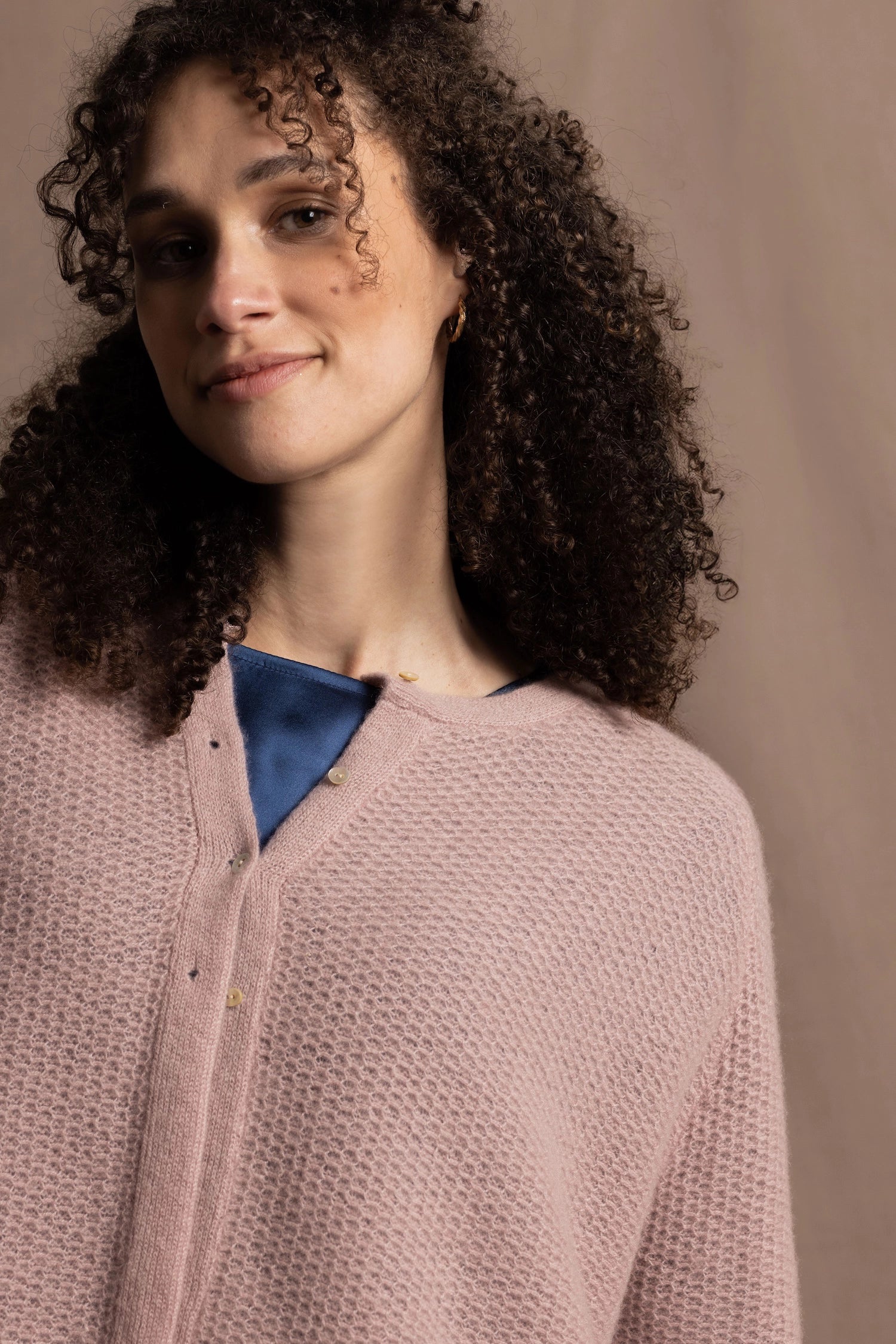 A close up shot of 100% cashmere button down swing cardigan with moss stitch texture in dusty pink