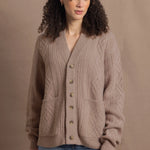 a woman wears a taupe coloured cashmere aran cardigan sweater with horn buttons