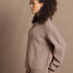 a woman wears a taupe coloured cashmere aran cardigan sweater with horn buttons