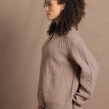 a woman wears a taupe coloured cashmere aran cardigan sweater with horn buttons