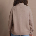 a woman wears a taupe coloured cashmere aran cardigan sweater with horn buttons