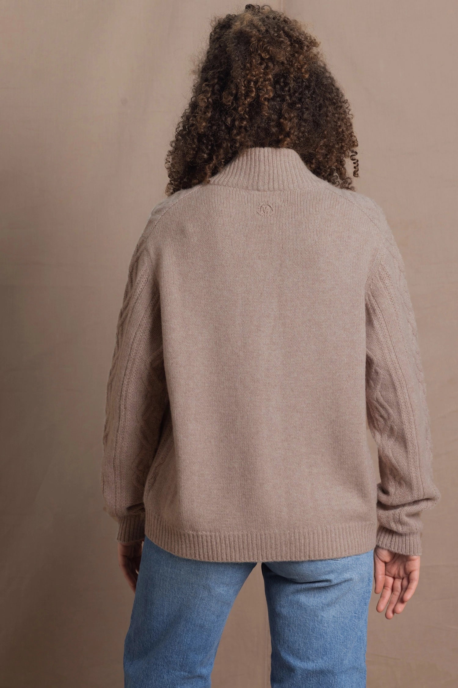 a woman wears a taupe coloured cashmere aran cardigan sweater with horn buttons