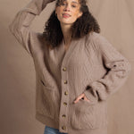a woman wears a taupe coloured cashmere aran cardigan sweater with horn buttons