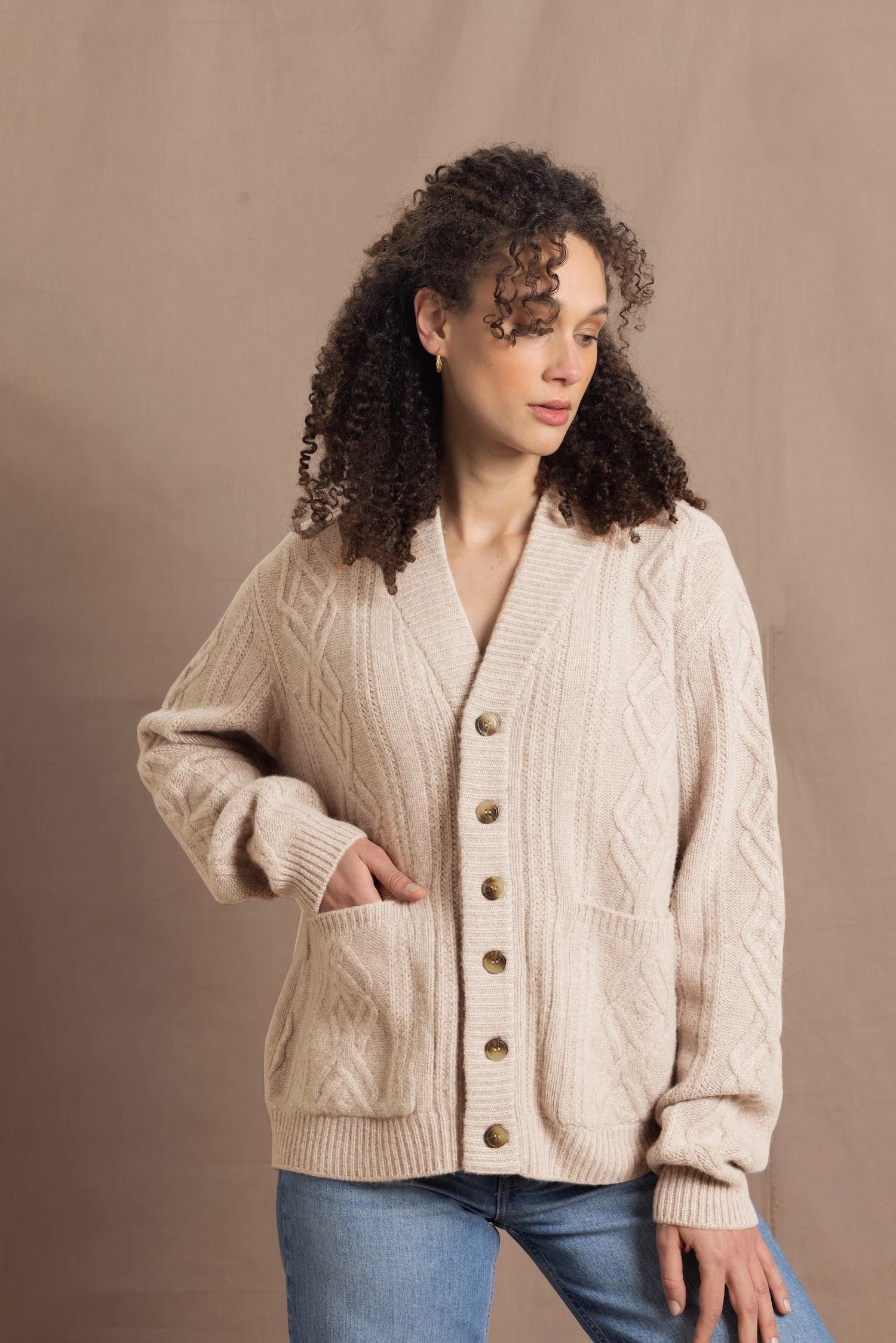 a woman wears a beige coloured cashmere aran cardigan sweater with horn buttons