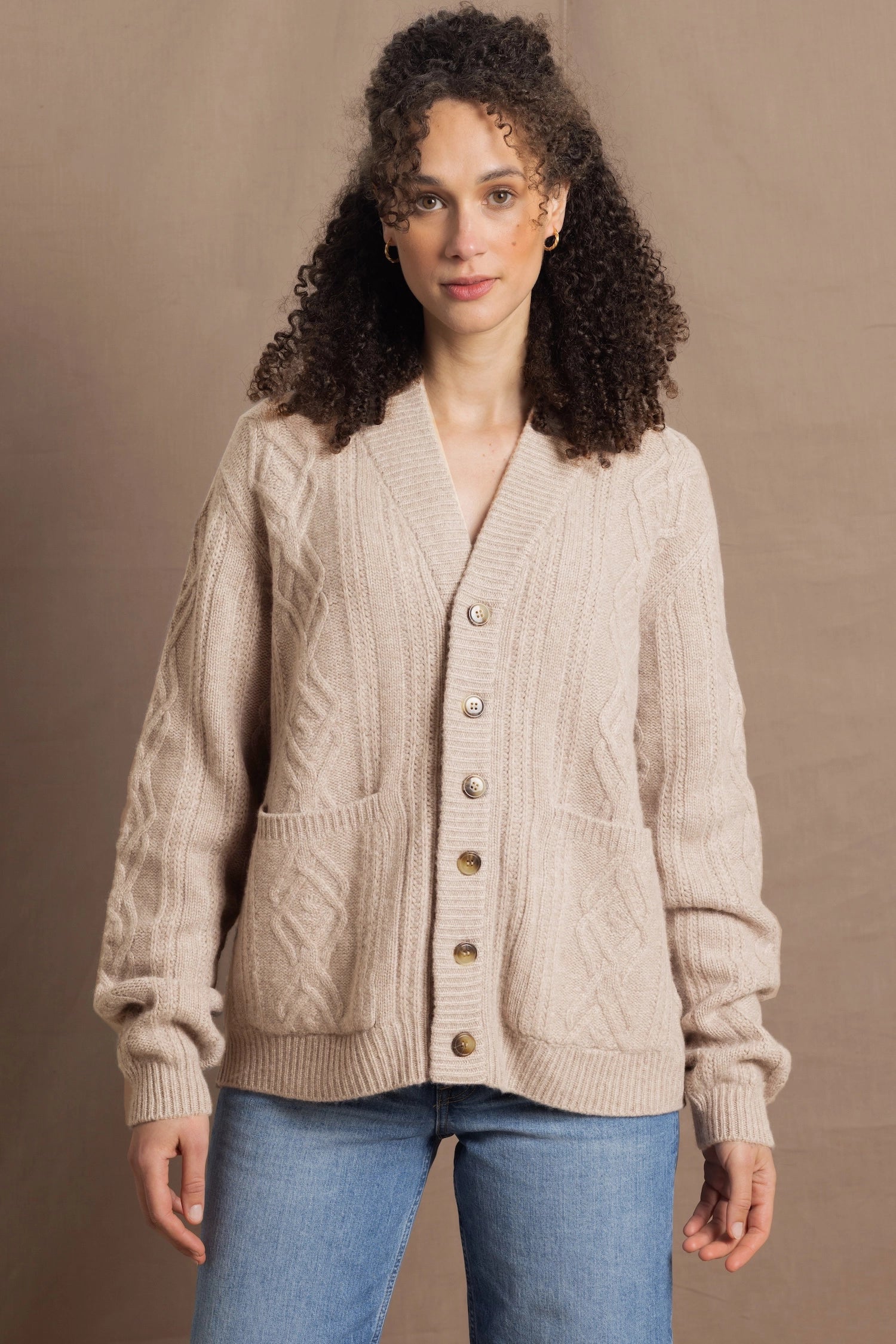 a woman wears a beige coloured cashmere aran cardigan sweater with horn buttons