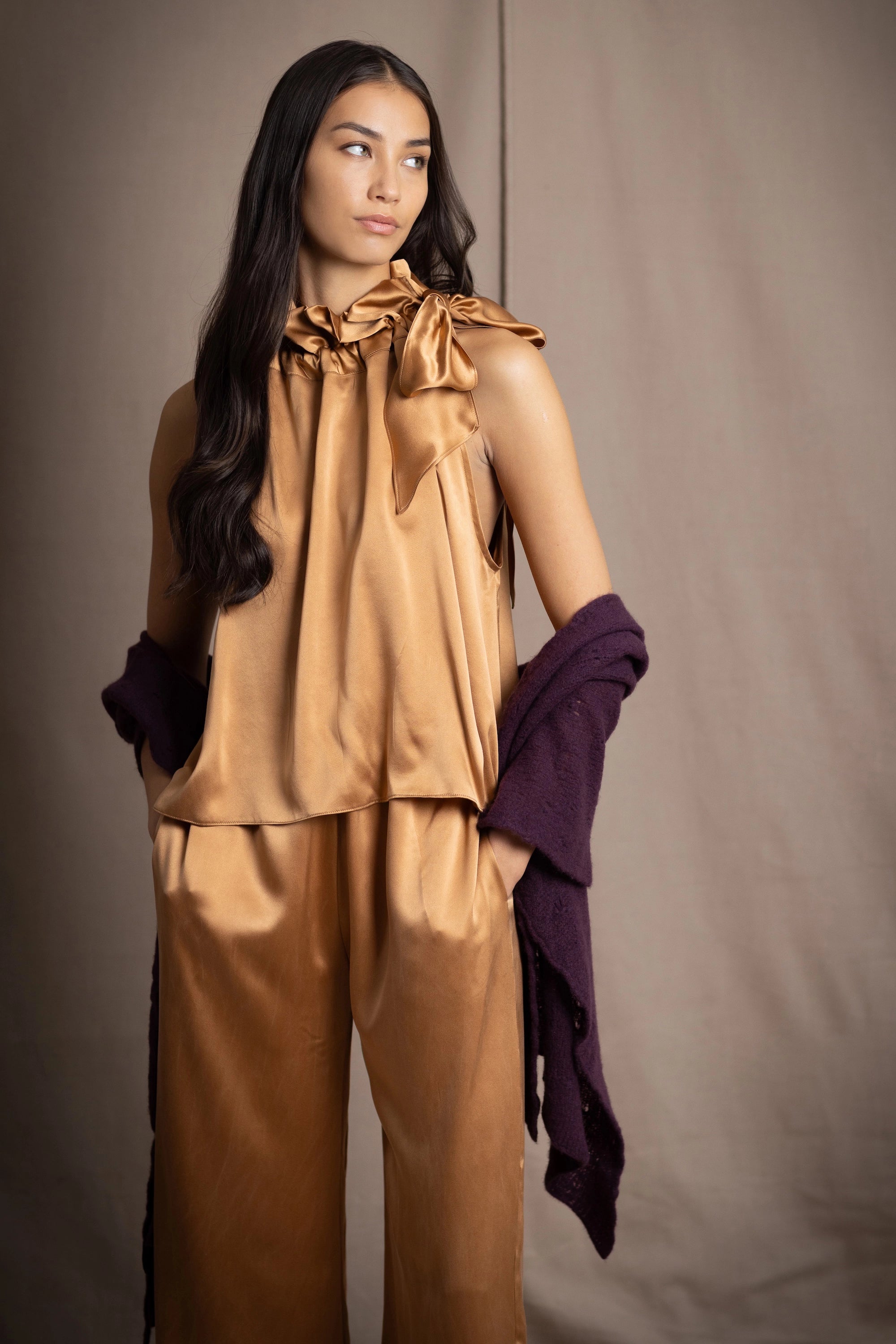 Woman wearing a dark purple cashmere lace wrap over bronze silk clothing
