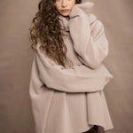 a woman wears an oversized 100% cashmere sweater in beige by Irish brand Madigan Cashmere
