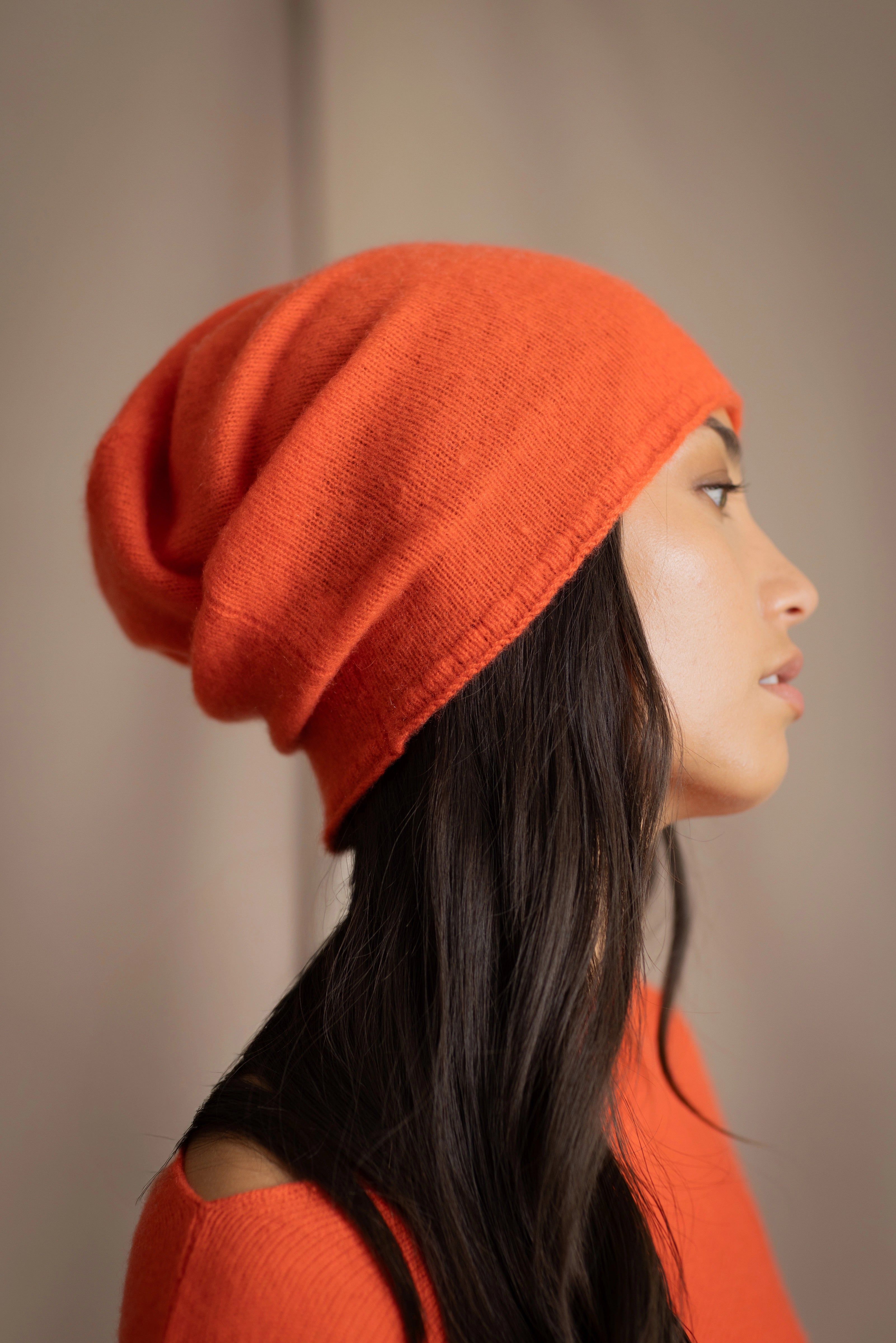 a woman wears a cashmere beanie hat in bright orange