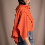 A woman wearing a bright orange  cashmere draped wrap shawl scarf by Irish brand Madigan Cashmere