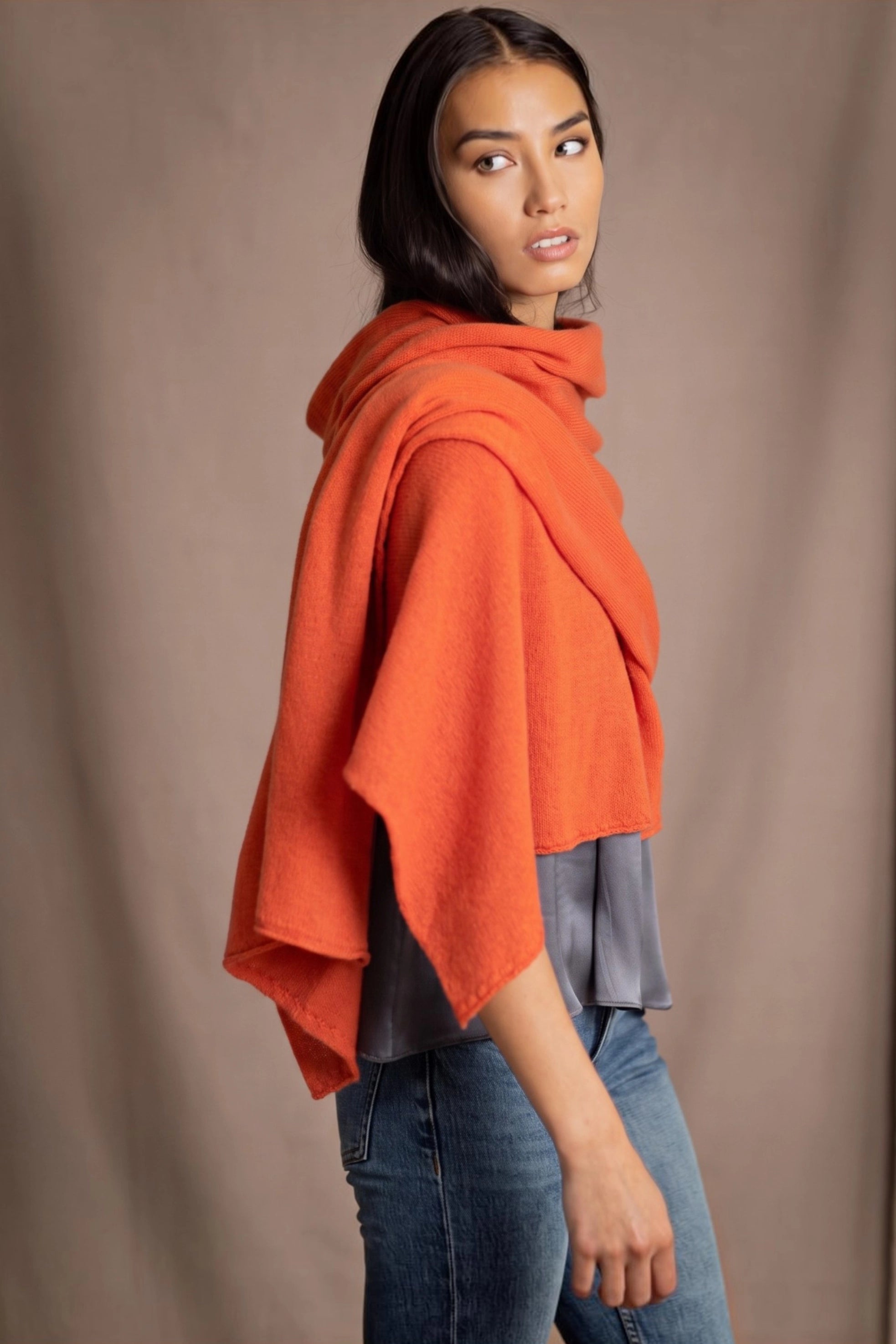 A woman wearing a bright orange  cashmere draped wrap shawl scarf by Irish brand Madigan Cashmere
