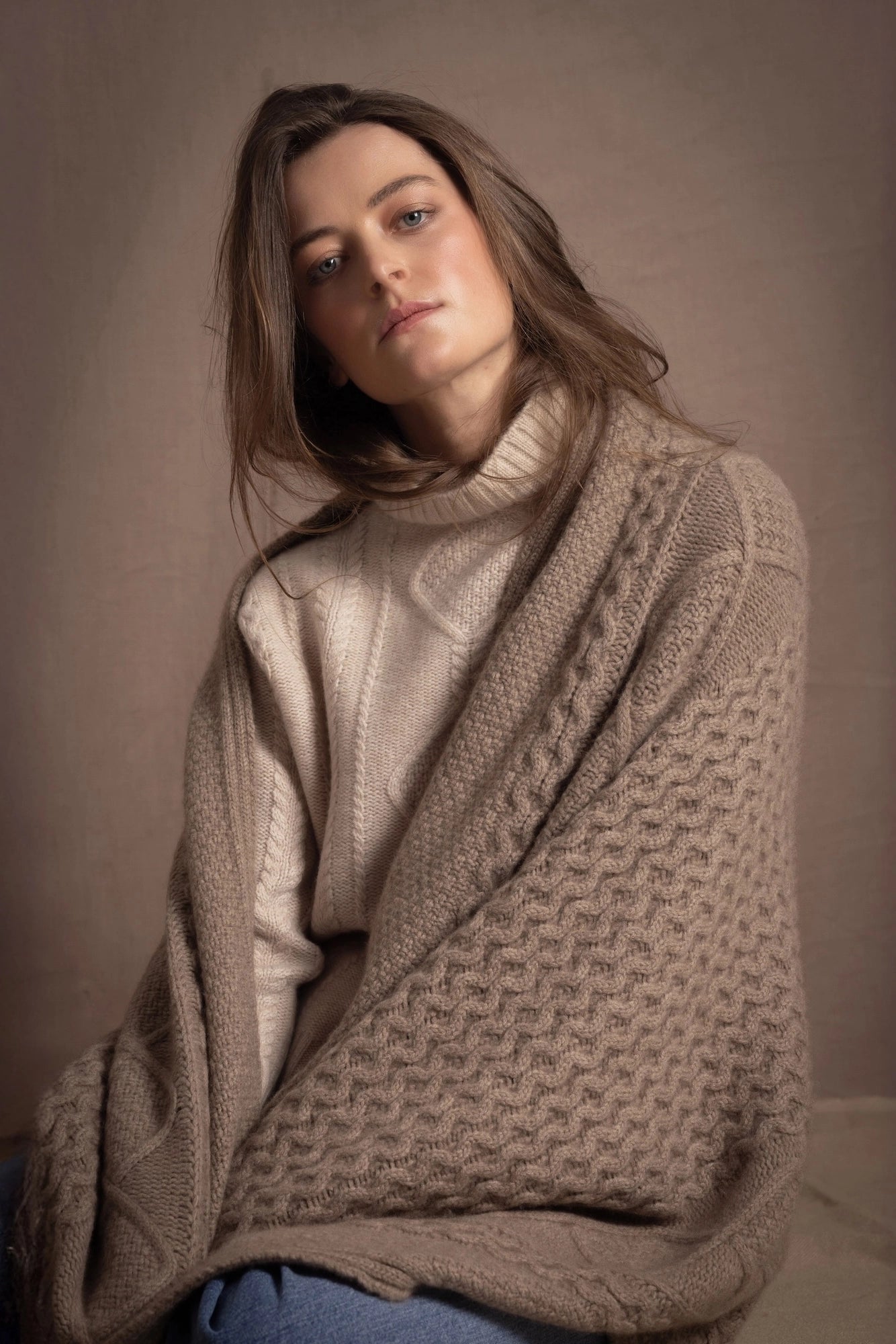 a woman wears a pure cashmere aran blanket throw over her