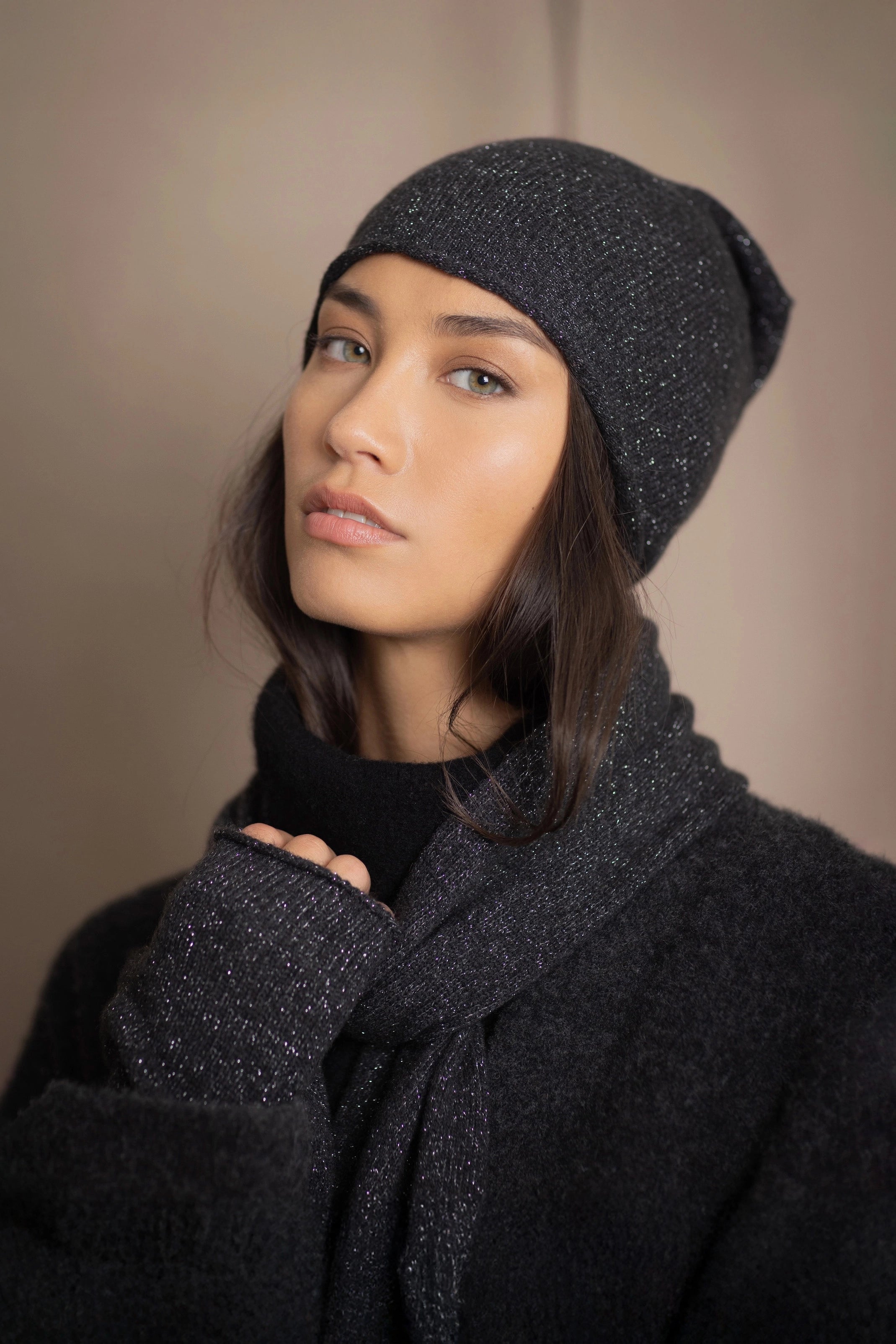 Woman wearing a black sparkly cashmere beanie hat with matching cashmere scarf and fingerless cashmere gloves