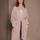 A woman wears a pure 100% cashmere dressing gown or robe in dusty pink
