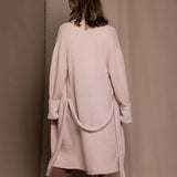 A woman wears a pure 100% cashmere dressing gown or robe in dusty pink