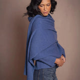 a woman wears a luxury cashmere wrap shawl scarf in blue over a matching cashmere sweater by Irish luxury brand Madigan Cashmere