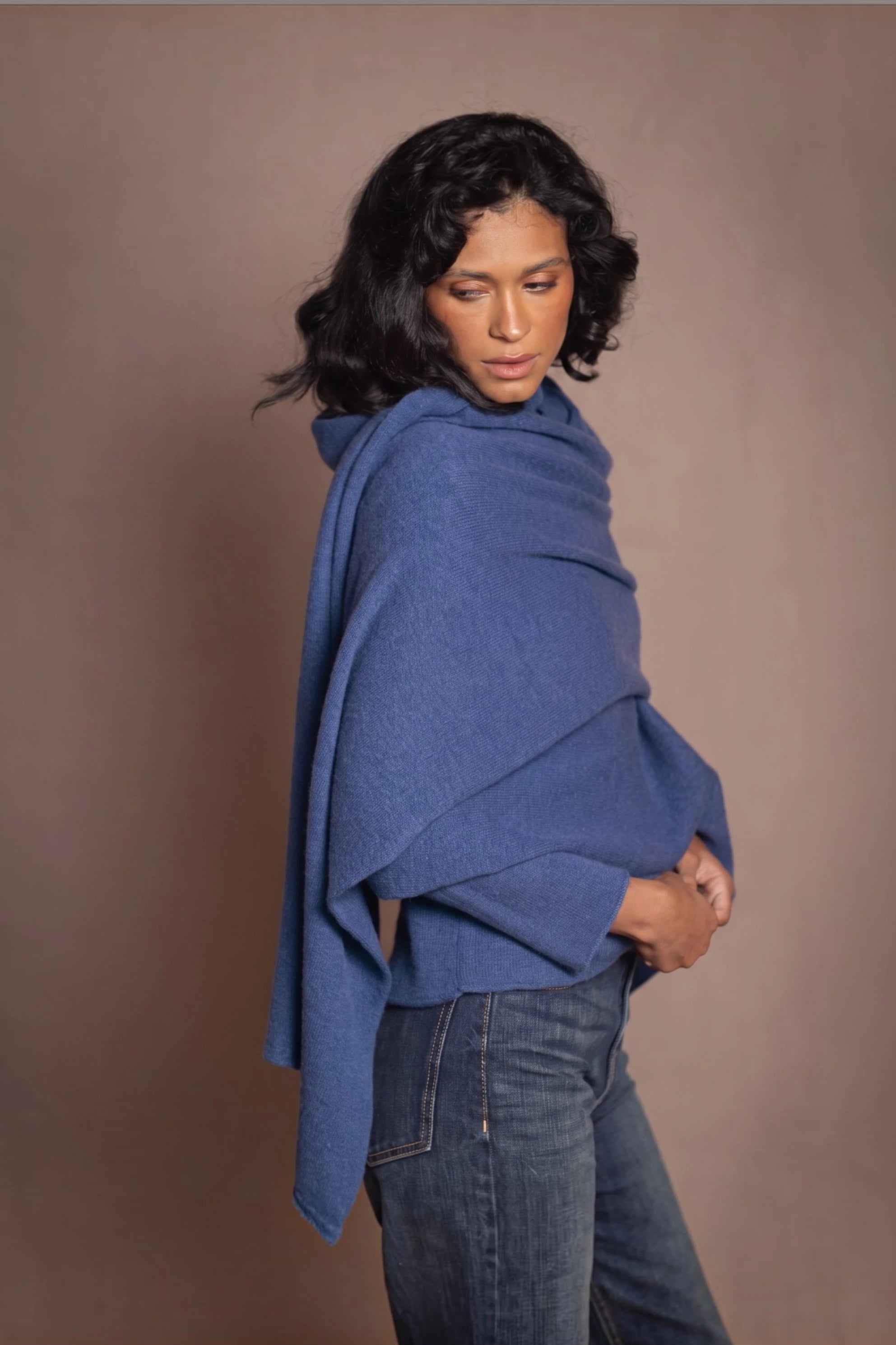 a woman wears a luxury cashmere wrap shawl scarf in blue over a matching cashmere sweater by Irish luxury brand Madigan Cashmere