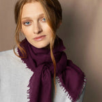 Woman wearing a lightweight cashmere scarf in plum