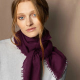 Woman wearing a lightweight cashmere scarf in plum