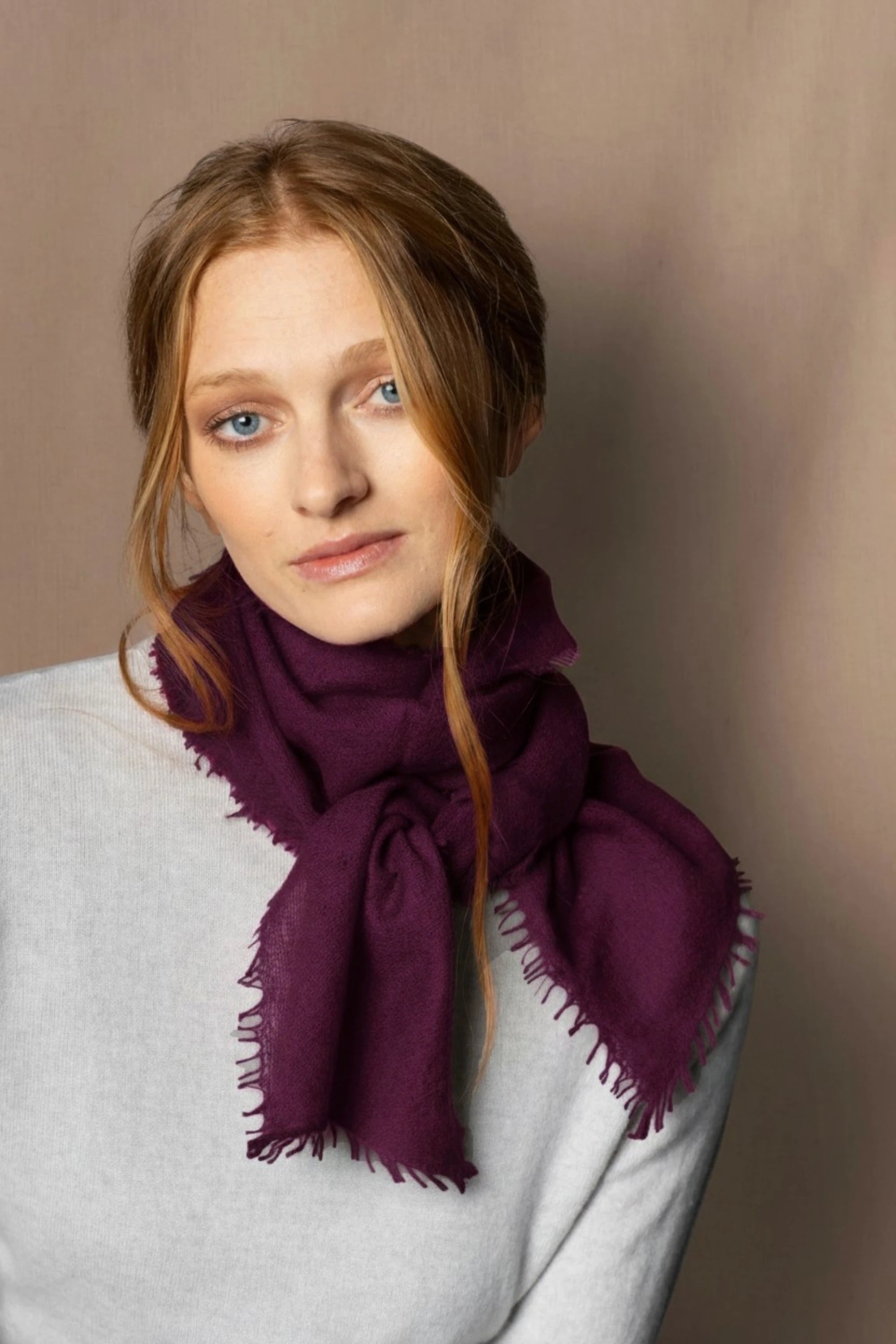 Woman wearing a lightweight cashmere scarf in plum