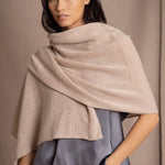 A woman wearing a beige cashmere wrap shawl draped over her shoulders by luxury Irish brand Madigan Cashmere