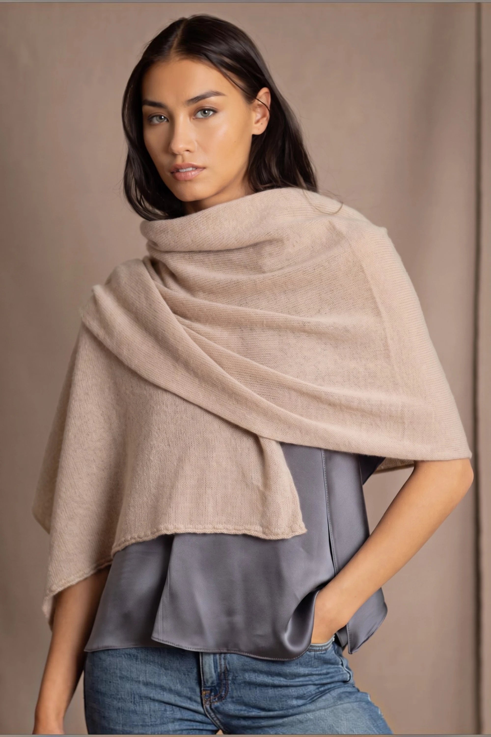 A woman wearing a beige cashmere wrap shawl draped over her shoulders by luxury Irish brand Madigan Cashmere