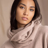 A woman wears a beige cashmere textured snood infinity scarf over beige cashmere sweater