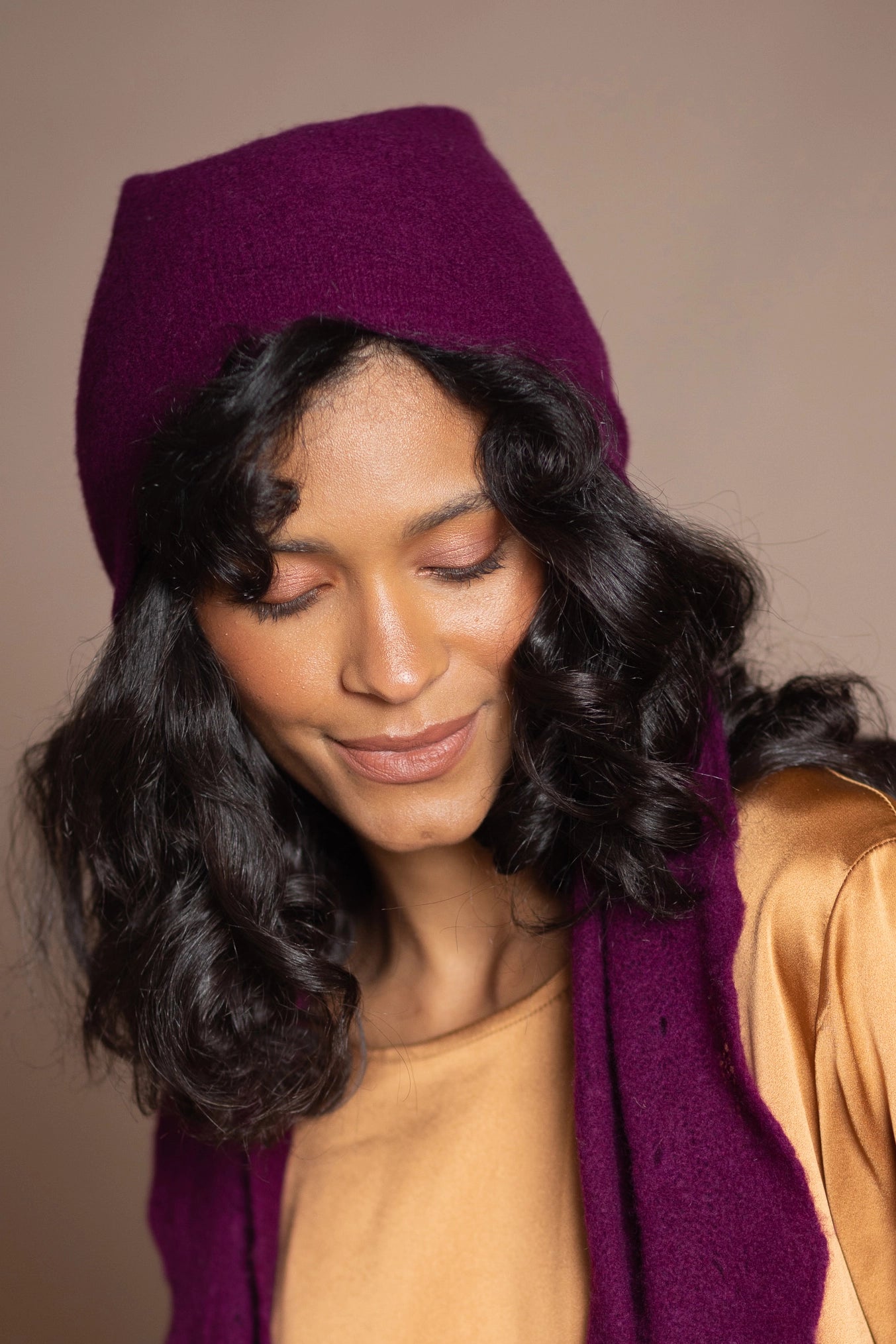 a woman wearing a textured luxury cashmere beanie hat in a burgundy plum colour by Irish luxury cashmere brand Madigan Cashmere