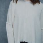 A woman wears an oversized 100% cashmere sweater in Ivory with black silk trousers