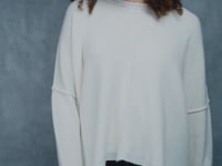 A woman wears an oversized 100% cashmere sweater in Ivory with black silk trousers